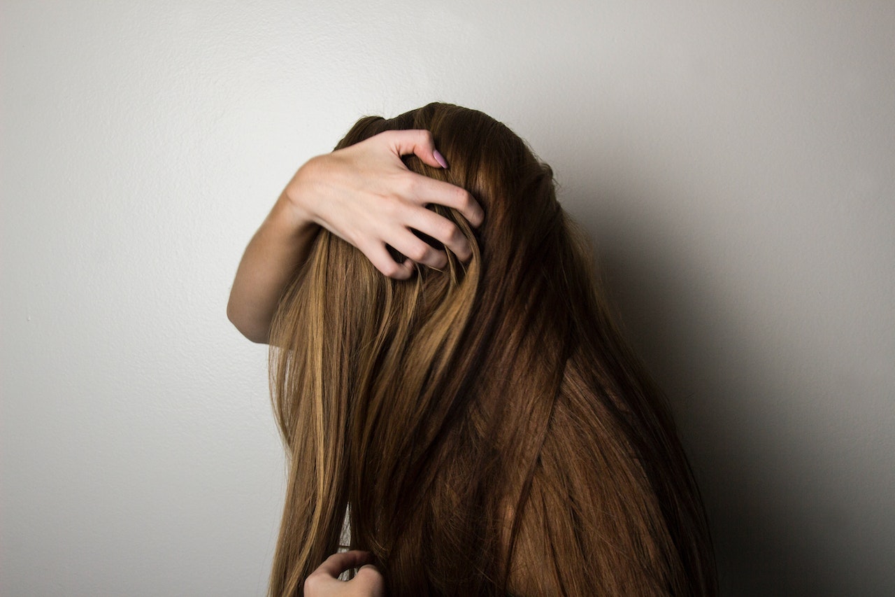 girl with long hair scratching head